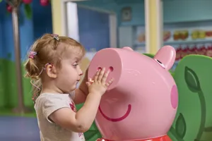 A young girl wit h visual impairment touches Peppa Pig